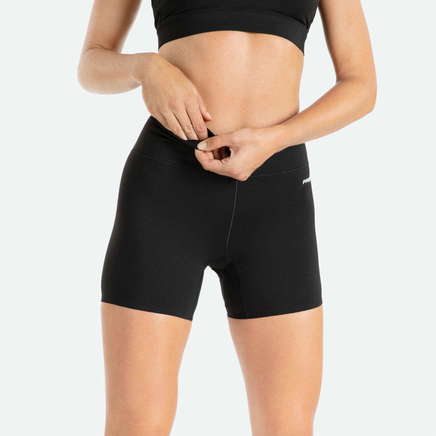 Pressio 3" korte tights for dame i fargen svart. Mid-rise. På modell, nærbilde forfra med lomme detaljer.