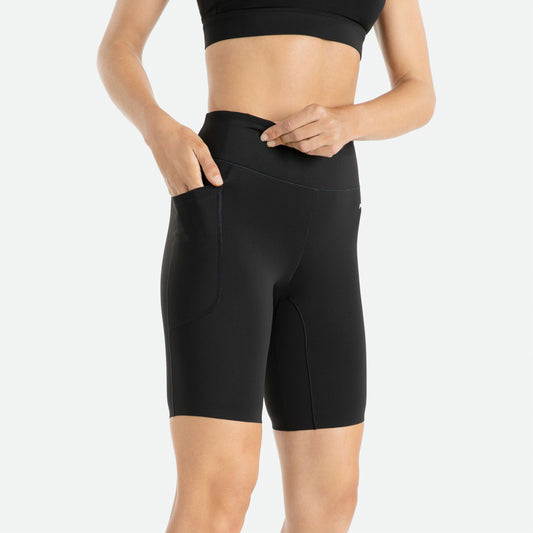 Pressio 5" korte tights for dame i fargen svart. Mid-rise. På modell fra siden, nærbilde. Viser lomme til f.eks. mobil på låret.