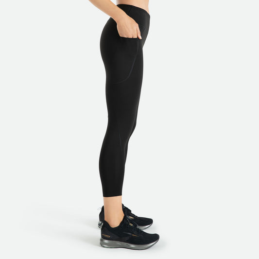Pressio 7/8 tights for dame i fargen svart. Mid-rise. På modell fra siden. Viser mobillomme på lår.