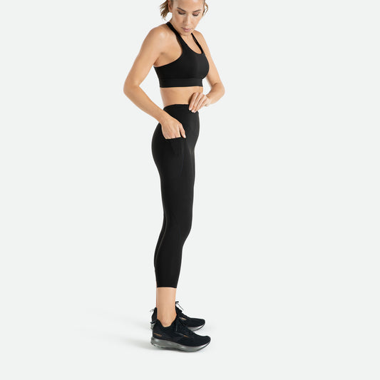 Pressio 7/8 tights for dame i fargen svart. High-rise. På modell fra siden. Viser mobillomme på lår.