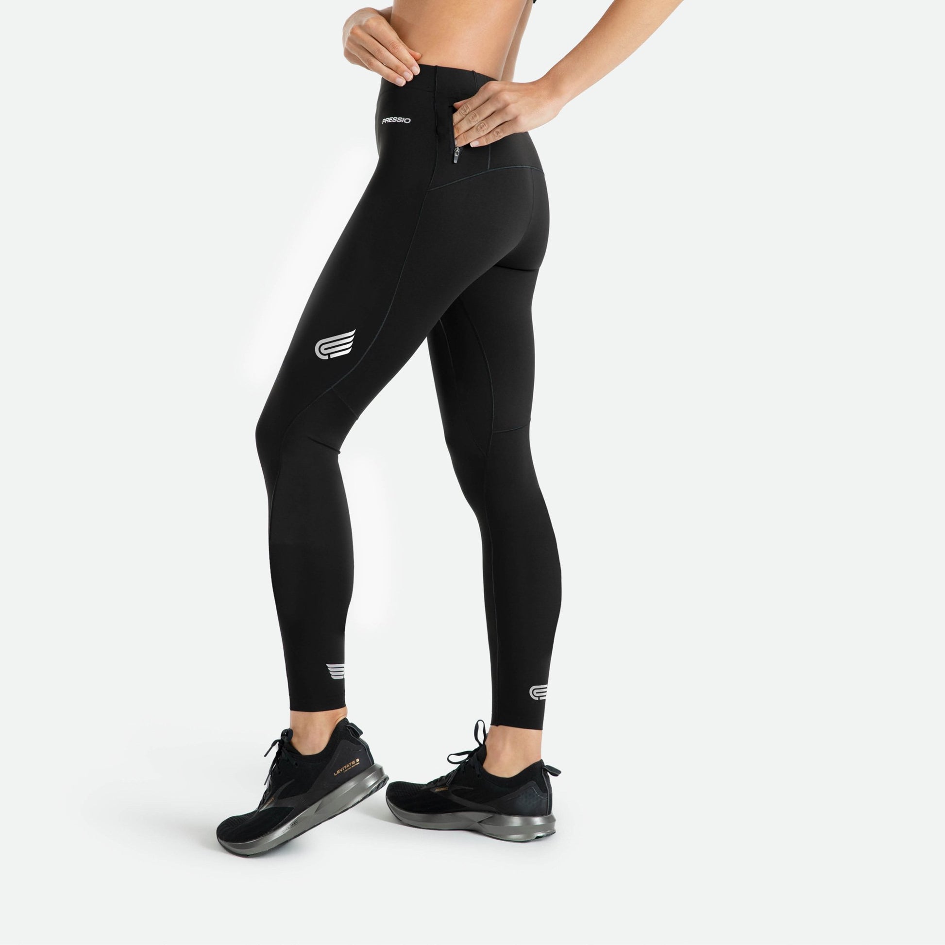 Pressio thermal løpetights for dame i fargen svart. Low-rise. Fra siden og viser liten lomme på modell med glidelås.